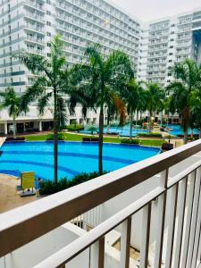 a view from a balcony of a swimming pool with palm trees at Shell Residences Manila by PauL in Manila