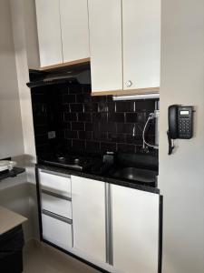 a kitchen with white cabinets and a phone on the wall at Studio miguel II in Rio de Janeiro