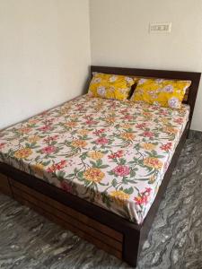 a bed with a floral quilt on it in a bedroom at Sai Srushti Homes in Gonikoppal +2 photos