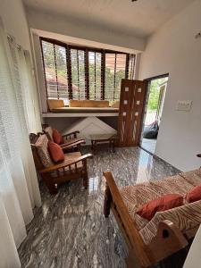 a room with two beds and a chair and a window at Sai Srushti Homes in Gonikoppal