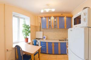 cocina con armarios azules, mesa y nevera en Kyiv apartment on Derevlyanskaya street close to the downtown, en Kiev