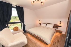 a bedroom with a bed and two chairs and a window at Serra Chalet in Fundata