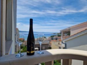 a bottle of wine and two glasses on a balcony at Dizma Welness Apartmani in Duće