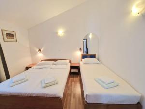 two beds in a room with white sheets and towels at Dizma Welness Apartmani in Duće +32 photos