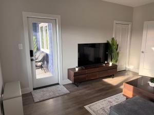 a living room with a flat screen tv and a table at Guest Suite in Langford in Goldstream Station
