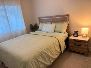 a bedroom with a large bed with a night stand and a window at Guest Suite in Langford in Goldstream Station