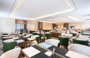 a dining room with tables and green chairs at ChillNow Hotel Guangzhou in Guangzhou