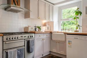 a white kitchen with a stove and a window at 3 Bed in Lydbrook oc-94490 in Lydbrook
