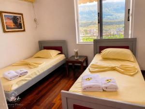two beds in a room with a window at Flowers House in Gjirokastër