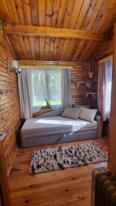 a room with a bed in a log cabin at Domek Szumin-Wywłoka in Majdan