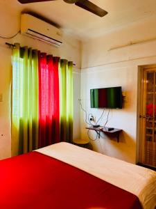 a bedroom with colorful curtains and a bed and a television at New Jtr Residency in Ernakulam