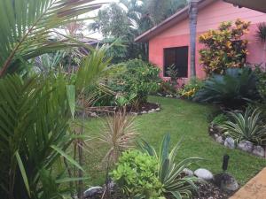 a garden in front of a pink house at Hacienda Cooya Beach in Mossman