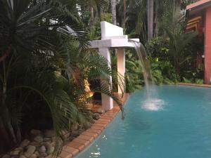 a swimming pool with a waterfall in a garden at Hacienda Cooya Beach in Mossman