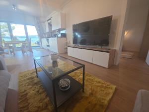 a living room with a large television and a glass table at Sunny Premium in Cristian