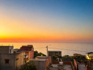 a view of the ocean at sunset from a city at Belle appart in Aguemoun Taïda