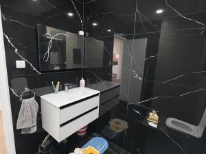 a black bathroom with a sink and a mirror at Belle appart in Aguemoun Taïda