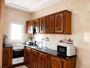 a kitchen with wooden cabinets and a microwave at Peace apartment in Brufut +34 photos
