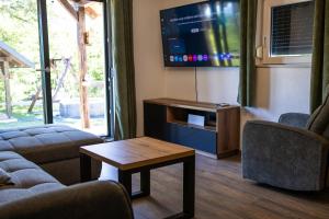 a living room with a tv and a couch and a table at Holiday House Štrbački buk in Donji Lapac