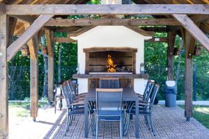 a patio with a table and chairs with a fireplace at Holiday House Štrbački buk in Donji Lapac