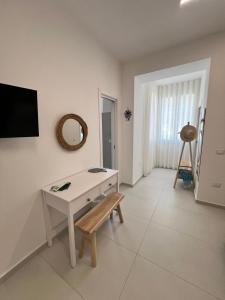 a white living room with a table and a mirror at Mamma mia rooms in Nola