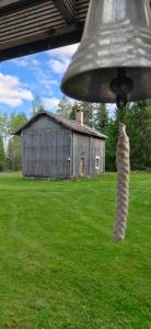 a bell in a field with an old barn at Raju - Guest House in Seinäjoki