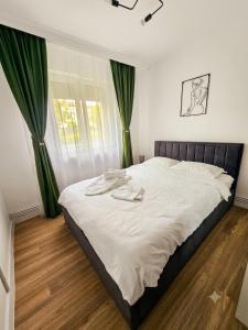a bedroom with a large white bed with green curtains at Cozy green apartament in Mediaş