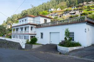 a white house with a balcony on top of a hill at Casa Borboleta in Arco da Calheta