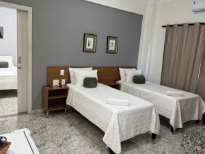 a hotel room with two beds with white sheets at Hotel Flor de Minas in Uberaba