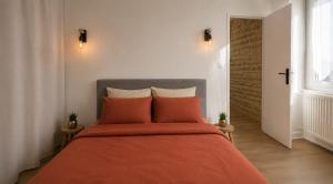 a bedroom with a bed with an orange blanket at L'Écrin de Pierre - Gare & Centre à pied - Charme & Calme in Mâcon