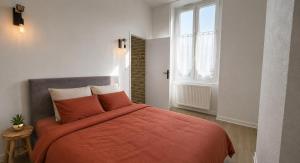 a bedroom with a bed with an orange blanket at L'Écrin de Pierre - Gare & Centre à pied - Charme & Calme in Mâcon