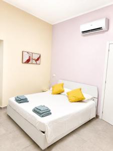 a white bedroom with a bed with yellow pillows at Dimora San Francesco in Sarzana