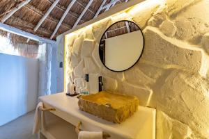 a bathroom with a mirror on a yellow wall at Hotel Qamar in Tulum +87 photos