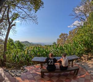 two people sitting on a picnic table looking out at the mountains at EL bosque mica in Minca