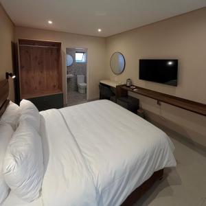 a bedroom with a large white bed and a bathroom at Thatch Haven in Mahikeng +2 photos