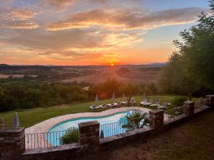 a pool with chairs and a sunset in the background at La Pietra Dorata in Rapolano Terme