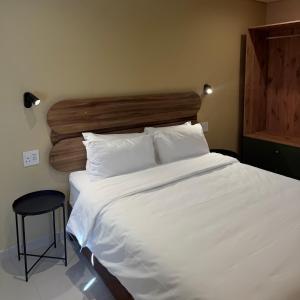 a bedroom with a large white bed with a wooden headboard at Thatch Haven in Mahikeng