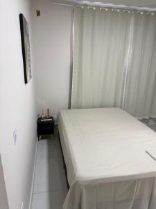 a small bedroom with a white bed and a window at Hostel do moreno in Vila Velha +4 photos