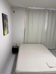a bedroom with a white bed and a window at Hostel do moreno in Vila Velha
