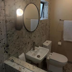 a bathroom with a sink and a toilet and a mirror at Thatch Haven in Mahikeng