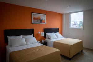 two beds in a hotel room with orange walls at ZAMORA EJECUTIVO EXPRESS in Zamora de Hidalgo