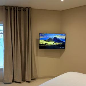 a television hanging on a wall next to a curtain at Thatch Haven in Mahikeng