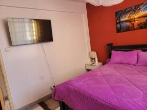 a bedroom with a purple bed and a window at Greatwall Apartment in Syokimau