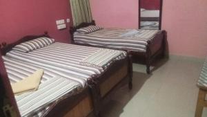 two twin beds in a room with pink walls at CHIDAMBARAM Bala Residency in Chidambaram