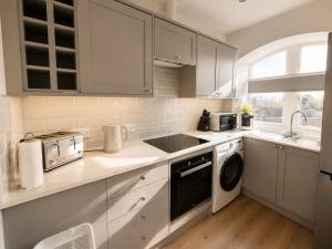 a white kitchen with a sink and a dishwasher at Comfortable Apartment set in an Old Mill in Westbury