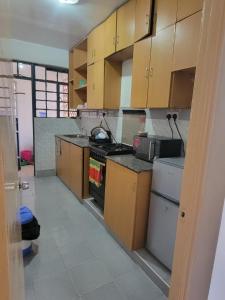 a kitchen with wooden cabinets and a stove at Greatwall Apartment in Syokimau