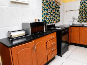 a kitchen with a stove and a microwave at JAC Tilama BNB Villa-3 Bedroom in Blantyre