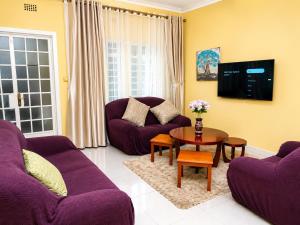 a living room with purple couches and a table at JAC Tilama BNB Villa-3 Bedroom in Blantyre