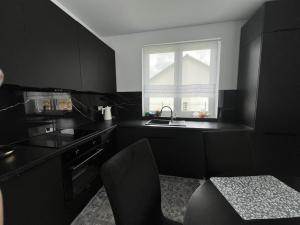a black kitchen with a sink and a window at DOM LAGOWSKI z SAUNA in Łagów