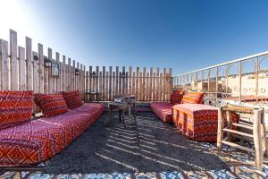 a room with couches and tables and a fence at Waves Hunter Surf House in Agadir