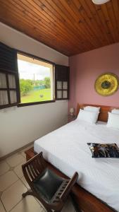 a bedroom with a bed and a chair and a window at Kéra Lodge in Rivière-Pilote